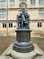 A statue of a man sitting on a chair in front of a building photo
