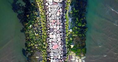 Large rock mass forms mole from beach to boundless sea video