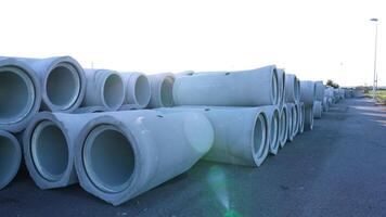 Pile of concrete pipes ready to install on asphalt ground video