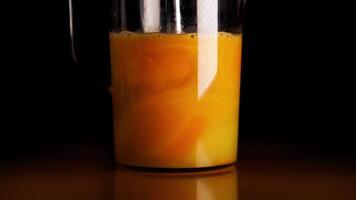 Whisking eggs in cup with mixer on table against darkness video