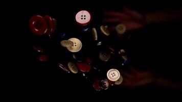 Person throws up coloured buttons of various size macro video
