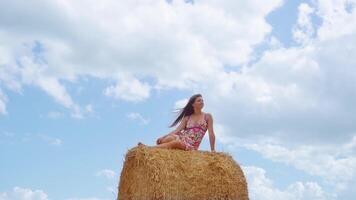 Girl sitting on the haystack on the background of the sky video