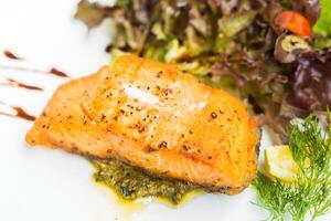 Salmon with pesto sauce and salad on white plate photo