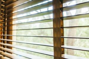 A window with wooden blinds and a view of trees photo