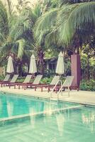 A pool with lounge chairs and umbrellas in front of a resort photo