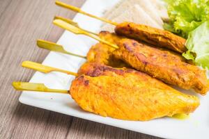 A plate with chicken skewers and salad photo