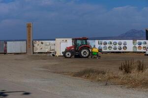 Rural landscape with red tractor and colorful artwork on containers under a clear blue sky photo