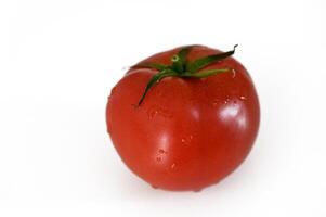 Fresh, ripe red tomato with dew glistening on its surface against a clean white background photo