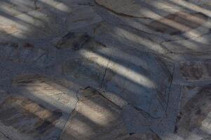 Shadows play on a rustic stone path under warm afternoon light in a serene outdoor setting photo