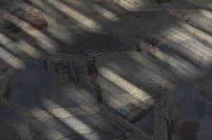 Shadows dance across textured stone paving in a tranquil outdoor space, capturing fleeting moments of light and form photo