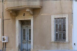 Charming weathered building facade with detailed wooden door and shutters in a quaint village setting photo