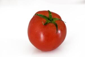 Ripe red tomato resting on a clean white surface, showcasing its vibrant color and fresh appearance photo