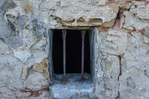 Old stone prison window with rusty bars in a historic building. photo