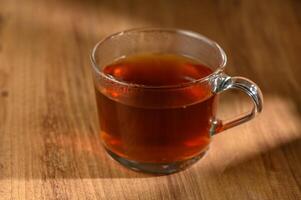 Cozy afternoon tea in a clear glass mug on a rustic wooden table inviting warmth and relaxation photo