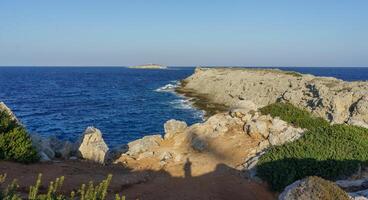 Coastal cliffs bathed in golden sunlight with turquoise waters at the edge of a tranquil horizon. photo