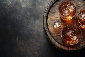 A well crafted whiskey bottle and glass with ice on a wooden barrel in a softly lit room photo