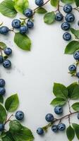 Fresh blueberries surrounded by green leaves arranged on a light background for a natural display photo