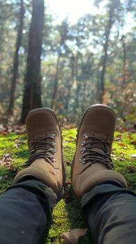 Person relaxing with hiking boots on soft moss under trees in a tranquil forest setting photo