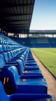 Empty blue stadium seats line the field under a clear sky during a sunny day photo