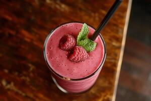 Refreshing raspberry smoothie with mint leaves on a wooden table in warm afternoon light photo