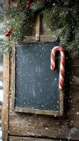 A rustic chalkboard adorned with a candy cane and snow during winter festivities outdoors photo
