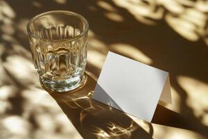 A clear glass with amber liquid next to a blank card on a softly lit table in a cozy setting photo