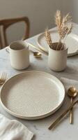 Elegant dining table setup featuring textured plates and gold utensils with dried flowers photo