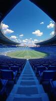 Empty blue stadium seats line the field under a clear sky during a sunny day photo