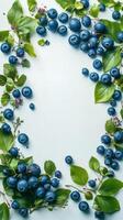Fresh blueberries surrounded by green leaves arranged on a light background for a natural display photo