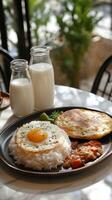 Delicious breakfast with fried eggs, rice, chicken, and drinks served at a cozy restaurant table photo