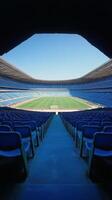 Empty blue stadium seats line the field under a clear sky during a sunny day photo