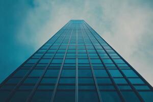 A towering skyscraper rises against a clouded sky in an urban landscape during daylight hours photo
