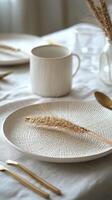 Elegant dining table setup featuring textured plates and gold utensils with dried flowers photo