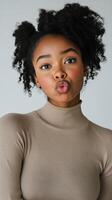 Young woman with curly hair making a playful expression against a simple background photo
