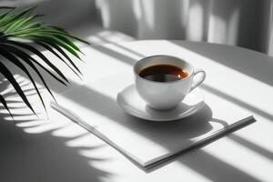 A white coffee cup sits on a small table next to a notepad in soft morning light photo