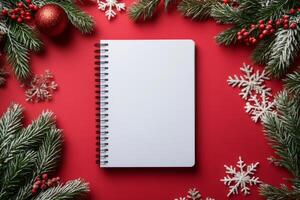 Blank notebook surrounded by Christmas decorations on vibrant red background photo