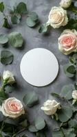 A circular arrangement of pastel roses and eucalyptus leaves on a textured gray surface photo