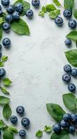 Fresh blueberries surrounded by green leaves arranged on a light background for a natural display photo