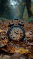 Antique clock resting on colorful fallen leaves in a serene forest during autumn photo