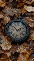 Antique clock resting on colorful fallen leaves in a serene forest during autumn photo