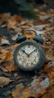 Antique clock resting on colorful fallen leaves in a serene forest during autumn photo