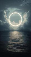 A bright circular light glowing through dramatic clouds over a calm ocean at dusk photo