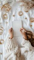 A young woman relaxing on a cozy bed while sketching in a notebook during a tranquil afternoon photo