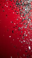 Shimmering silver confetti scattered on vivid red background for festive celebrations photo
