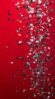 Shimmering silver confetti scattered on vivid red background for festive celebrations photo
