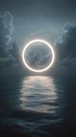 A bright circular light glowing through dramatic clouds over a calm ocean at dusk photo
