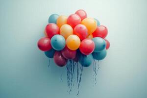 Colorful balloons resting against a white wall on a bright sunny day in an urban area photo