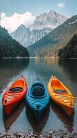 Colorful kayaks float gently on serene water amidst majestic mountains and lush forests in summer photo