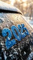 Snow covered vehicle displaying the year 2025 during a winter morning in a rural area photo