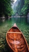 Calm wooden canoe resting on clear water surrounded by lush trees in a tranquil setting photo
